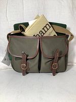 Front view showing two front pockets with leather straps and brass buckles