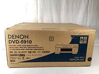 Front face of sealed cardboard retail box displaying Denon branding, model number and illustrative unit diagram with feature icons.