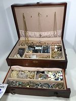 Open wood jewelry box with top hooks holding necklaces, compartments with rings, pins; bottom drawer holds bracelets, beaded necklaces.