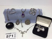 Overview of all 10 jewelry pieces including pendants, chains, ring, earrings, and pin displayed on a fabric stand and black ring holder.