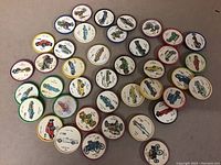 Photo showing 40 round collectible cardboard discs featuring vintage automobile illustrations from the 1960s/70s, each with different vehicles and colored borders.