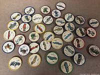 37 round collectible discs with vintage automobile images and numbers, arranged on a flat surface.