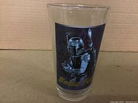 Front view of clear tall drinking glass featuring colored graphic of Boba Fett in armor, holding a weapon, with yellow text 'Boba Fett' below the image.