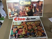 Photo showing both Clue and Clue Jr. board games in their original boxes with visible artwork.
