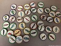 Forty round JELLO collectible discs featuring various vintage automobile illustrations from the 1960s and 1970s, arranged in rows on a surface. Each disc has a colored rim and printed car image.