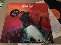 Vinyl LP 'Bat Out of Hell' by Meat Loaf showing front album cover artwork and partially visible vinyl record with orange label.