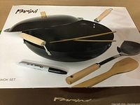Photo of boxed Parini 5-piece wok set showing wok pan with lid and utensils on packaging.
