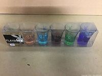 Full set of six colored Playboy Bunny shot glasses in original clear plastic box with Playboy logo label.
