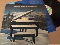 Photo of the Supertramp LP album cover for Even In The Quietest Moments showing snowy outdoor scene with grand piano.
