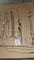 Photo showing a broad view of multiple long chain style necklaces, some with beads and pendants in various colors and materials.