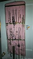 Full view of assorted necklaces hung on a pink fabric display showing variety in colors and styles, including multi-strand and beaded designs