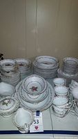Photo showing assorted pieces of the HIRA Ridgewood china laid out on table with multiple stacks of plates, cups, and bowls.