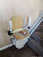 Chair unit folded at bottom of staircase with beige seat and rail sections visible