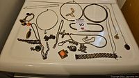 Overview of lot: multiple silver necklaces, bracelets, pendants, earrings and charm on white surface