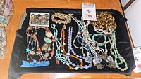 Full lot view of Southwestern style necklaces and bracelets with mixed stones on black surface, including stamped 925 silver pieces