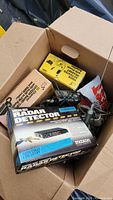 Photo of open box containing boxed radar detector, voice operated switch, and assorted cables and devices