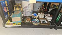 Photo showing assortment of mid century decor items on shelf including boxes, carry bag, ceramic dishes, planters and pottery.
