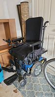 Front-right angle view of the blue and black Quantum J4 wheelchair showing padded seat, armrests, joystick control, front wheels, and footrest.