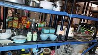Overview of glassware on shelving including jadeite shakers, Delphite Blue bowls, Pyrex refrigerator dishes.