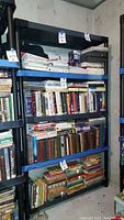 Full view of tall four-tier plastic shelving unit filled with books and miscellaneous items to show scale, condition, and structure