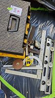 Contents next to the toolbox showing various metal measuring tools including rulers, tape measure, plumb bob, hand plane, level, 90-degree square and angle finder