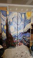 Four-panel canvas room divider showing Van Gogh Starry Night scene with swirling night sky, prominent dark cypress trees, and village.