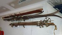 Full view of two sets of wooden skis and poles hanging on pegboard.