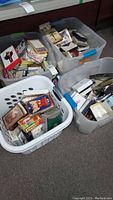 View showing white laundry hamper and multiple plastic bins filled with assorted greeting cards and stationery items