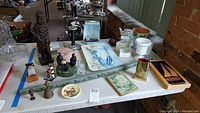 Overview of lot including carved figurines, serving tray, flower pot, and awards on table