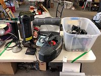 Full lot overview on table including stereo, fans, air purifier, lamp, antenna, and electronics bin