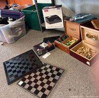 Two glass chess boards laid flat showing checkered patterns; two wooden humidors open with cigar corks and hygrometers visible; Gadget Smarts charging station box behind them; playing cards and chess pieces included.