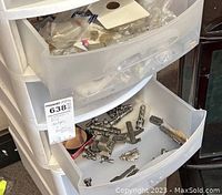 Close-up of open drawer showing pewter miniature figures including a cross, buildings, animals, and other small sculptures.