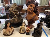 Overview of the lot showing all sculptures and figurines on a table indoors with natural light.