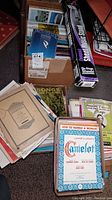 Boxes and stacks of sheet music with visible titles and a box of books including The Providence Journal.