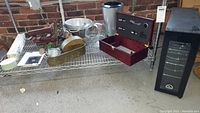 Photo showing assorted kitchenware, metal planters, and decorative wine accessories on wire rack