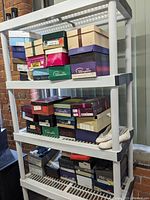 Shelf with multiple stacked shoe boxes from various brands, showing a quantity of women's footwear boxes and some shoes.
