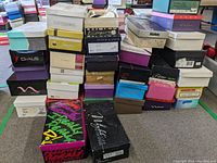 Stacks of assorted women's shoe boxes including multiple known brands like Claiborne, Peter Kaiser, and others showing shoe box tops and sides.