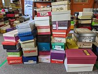 Photo of stacked shoe boxes showing variety of women's footwear brands and styles with multiple boxes visible
