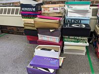 Stack of multiple women's shoe boxes showing brand labels and varied styles, mostly size 8.