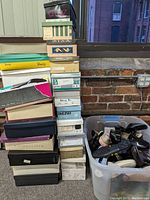 Stacked shoeboxes with various brand labels and a plastic bin filled with multiple pairs of shoes.