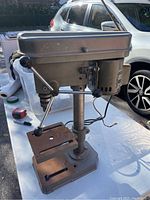 Full view of the American Forge & Foundry industrial bench drill press showing metal frame, worktable, lever handles, and attached light assembly.