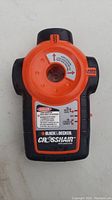 Front view of the Black & Decker Crosshair auto laser level showing the orange circular laser housing, control dial, warning labels and brand name.