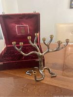 Silver plated menorah on wooden table beside open wine-colored velvet storage box