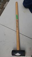 Full length view of sledgehammer on white surface showing wooden handle and black metal head