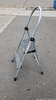 Side angle view of the metal 2-step ladder showing the frame, steps, and handlebar.