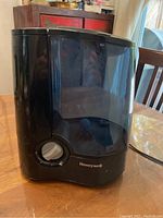 Front view of the black Honeywell humidifier with control knob and translucent water tank.