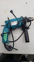Left side view of Makita concrete drill with visible label and power cord wrapped around.