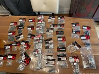 Wide view of all packaged Gibraltar drum hardware items arranged on a table showing various small parts in plastic packaging.