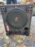 Front view of the Optimus subwoofer showing 12-inch speaker with black metal grille, carpeted box, and molded plastic feet.