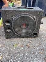 Front view of Rockford Fosgate speaker showing main driver with metal grille and two smaller horn tweeters alongside port hole.